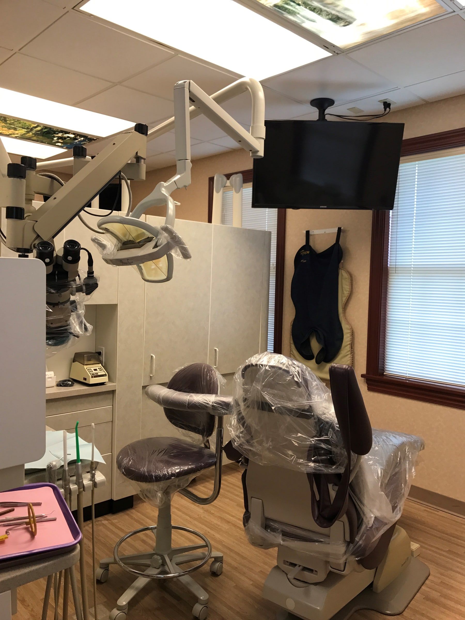 A treatment room with the surgical operating microscope beside the dental light and chair